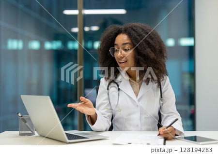 A female doctor conducts a telehealth consultation, explaining the details to the patient while taking notes. 128194283
