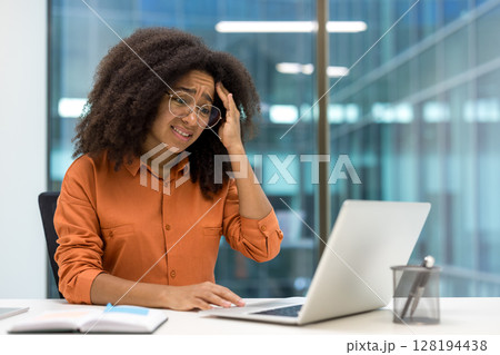 Upset frustrated woman working with laptop inside office. Businesswoman unsatisfied reading online email notification message from laptop. 128194438