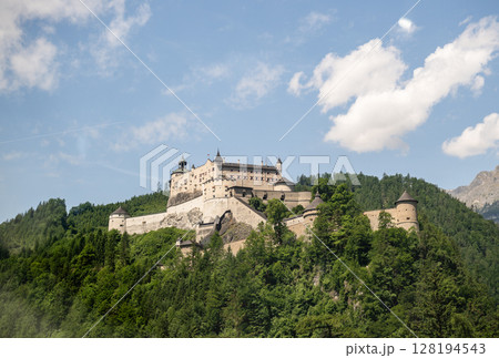 Medieval fortress Hohenwerfen Castle on green forested hill in Austrian Alps 128194543