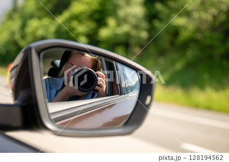 Photographer taking picture reflected in car side mirror on sunny day 128194562