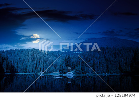 scenic landscape with lake among coniferous forest at night. tranquil reflection of primeval woodland in mountains in full moon light scenic landscape with lake among coniferous forest at night. tranquil reflection of primeval woodland in mountains in full moon light 128194974