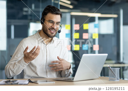 Business professional wearing headset in virtual meeting, engaging in remote conversation using laptop. Modern office setup highlights digital communication efficiency. Suitable for business context. 128195211