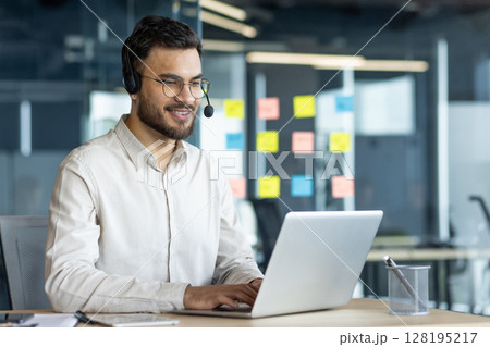 Latin American businessman working efficiently on a laptop wearing a headset in office environment, demonstrating effective remote communication, work engagement, and business professionalism. Latin American businessman working efficiently on a laptop wearing a headset in office environment, demonstrating effective remote communication, work engagement, and business professionalism. 128195217