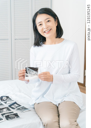 寝室でエコー写真を見ながら赤ちゃんが生まれてくるのを待ち望んでいる母と娘 寝室でエコー写真を見ながら赤ちゃんが生まれてくるのを待ち望んでいる母と娘 128195245