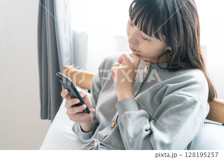 寝室で出産の準備に向けたリストを確認している妊婦 128195257