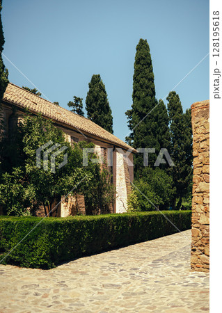 Charming rustic villa surrounded by lush greenery under a clear sky. Charming rustic villa surrounded by lush greenery under a clear sky. 128195618