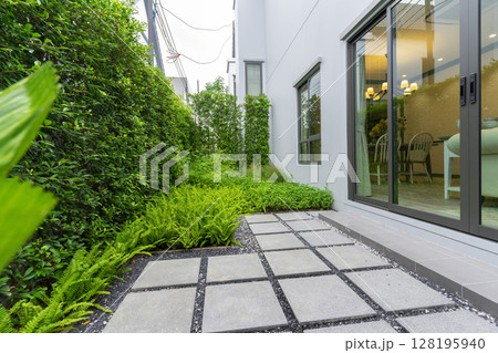 Modern design home garden landscaping. Flower garden and green plant with brick border and pedestrian pathway. 128195940