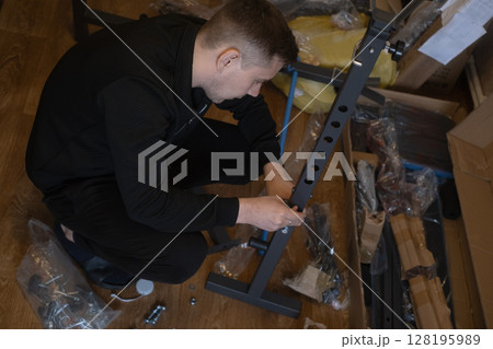 Assembling fitness equipment indoors to create a home gym for health and convenient workouts. Assembling fitness equipment indoors to create a home gym for health and convenient workouts. 128195989