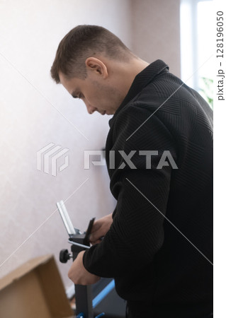 Furniture assembly specialist working at home carefully installing parts creating a functional and organized interior. 128196050