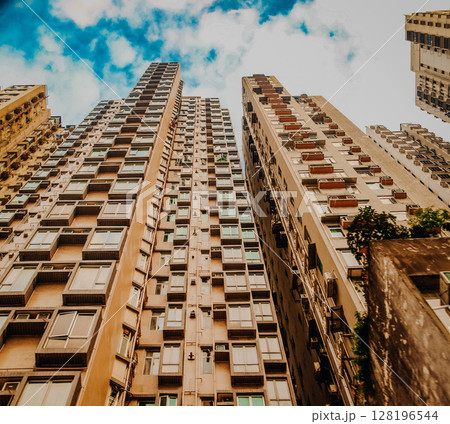 Dense High-Rise Residential Buildings In Hong Kong: Towering Urban Skyline With Layers Of Modern Apartments Under A Cloudy Sky In One Of The Worlds Most Populated Cities. Dense High-Rise Residential Buildings In Hong Kong: Towering Urban Skyline With Layers Of Modern Apartments Under A Cloudy Sky In One Of The Worlds Most Populated Cities. 128196544