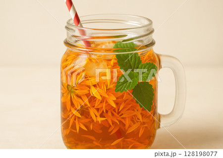 Chilled herbal tea with yellow flower petals and fresh mint leaves served in a mason jar with ice cubes and striped straw, AI Generative 128198077
