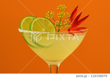 Refreshing margarita cocktail garnished with lime slices, flower, and herbs in a glass against a vibrant orange background, AI Generative 128198078