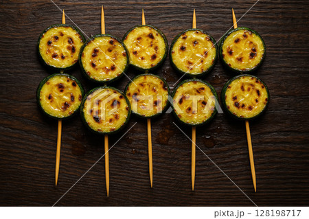 Grilled zucchini skewers arranged in a pattern on dark wooden surface, showcasing charred marks and vibrant colors, AI Generative Grilled zucchini skewers arranged in a pattern on dark wooden surface, showcasing charred marks and vibrant colors, AI Generative 128198717