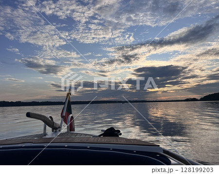 Sunset view of the back of a cruise ship with seating areas and the wake behind the ship Sunset view of the back of a cruise ship with seating areas and the wake behind the ship 128199203