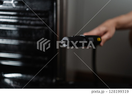 Housekeeper preparing steam cleaner for efficient cleaning of gas oven in kitchen, focusing on maintaining hygiene and ensuring spotless, sanitized environment. Concept of housekeeping domestic life. 128199319