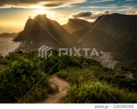 Golden Sunset Over Rio De Janeiro From Two Brothers Mountain: Dramatic Sunbeams Streaming Through Coastal Peaks Above The Atlantic Ocean And Leblon Beach Golden Sunset Over Rio De Janeiro From Two Brothers Mountain: Dramatic Sunbeams Streaming Through Coastal Peaks Above The Atlantic Ocean And Leblon Beach 128200308