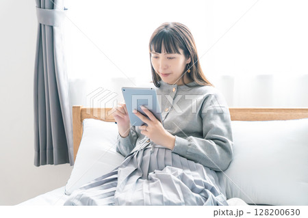 寝室でタブレットを見ながら出産準備をする妊婦 寝室でタブレットを見ながら出産準備をする妊婦 128200630