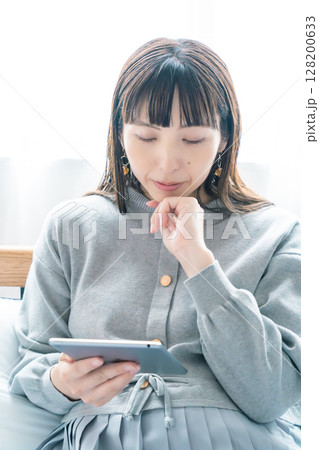 寝室でタブレットを見ながら出産準備をする妊婦 128200633