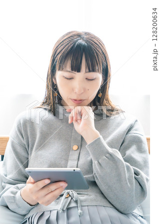 寝室でタブレットを見ながら出産準備をする妊婦 寝室でタブレットを見ながら出産準備をする妊婦 128200634