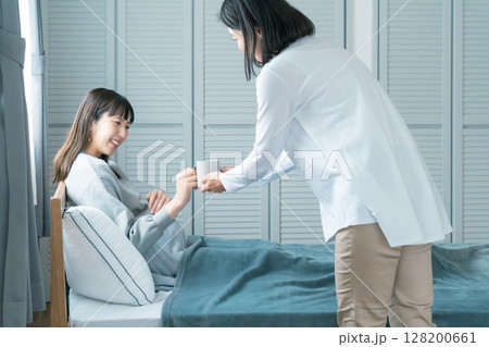 妊娠している娘に飲み物を渡す母 妊娠している娘に飲み物を渡す母 128200661