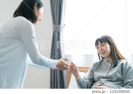 妊娠している娘に飲み物を渡す母 128200680
