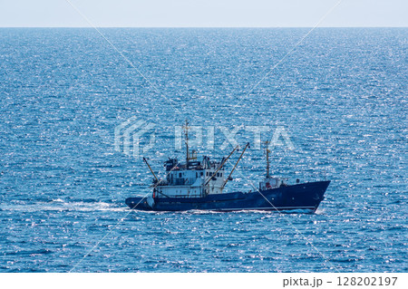 Fishing boat in blue sea and clear sky with birds flying overhead. Fishing boat in blue sea and clear sky with birds flying overhead. 128202197