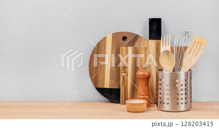 Wooden and metal kitchen utensils arranged on a clean countertop create a minimal and modern cooking atmosphere ready for meal preparation 128203415