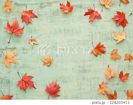 Distressed blue wooden background adorned with vibrant autumn maple leaves. 128203451