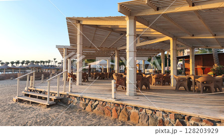 A wooden beach resort restaurant by the Red Sea in Egypt. The structure features outdoor seating and a sandy beach, ideal for summer relaxation. 128203929