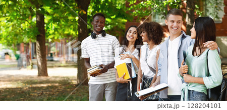 Group of international students standing together outdoors in college campus, chatting and laughing, free space 128204101
