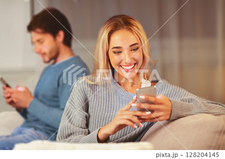 Cheating. Unfaithful Girlfriend Chatting On Phone With Lover Sitting Next To Boyfriend On Couch Indoor. Selective Focus Cheating. Unfaithful Girlfriend Chatting On Phone With Lover Sitting Next To Boyfriend On Couch Indoor. Selective Focus 128204145