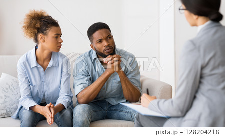 Marital Therapy. Black Couple Listening To Counselor's Advice Sitting On Couch In Office. Marital Therapy. Black Couple Listening To Counselor's Advice Sitting On Couch In Office. 128204218