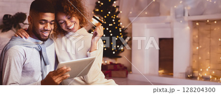 Christmas holiday. African-american couple choosing gifts on tablet, using credit card 128204300