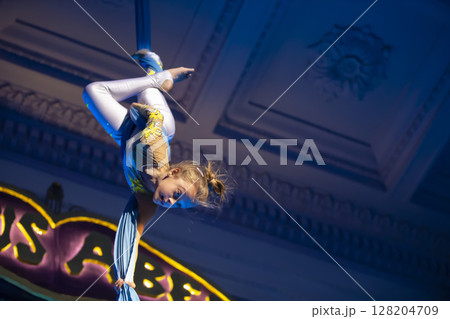 The girl performs acrobatic numbers on the canvases. A small circus artist performs on the canvases of acrobats. Child perform acrobatic elements in the air 128204709
