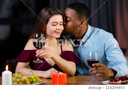Dinner For Two. Loving Interracial Couple Dining At Home In Romantic Atmosphere, Drinking Wine, Celebrating Valentine's Day Or Anniversary Together, Black Boyfriend Whispering Love Words To Girfriend 128204953