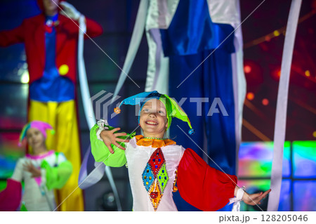 Little girl is dancing in a clown costume. The child performs on stage. 128205046