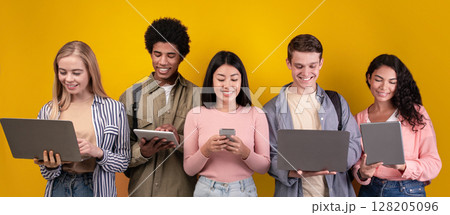 Education, knowledge, modern gadgets in college and social networks. Smiling young multiracial students studying, using digital devices, isolated on orange background, copy space, studio shot Education, knowledge, modern gadgets in college and social networks. Smiling young multiracial students studying, using digital devices, isolated on orange background, copy space, studio shot 128205096