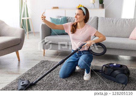 Young housewife taking selfie with smartphone while cleaning up her house, full length portrait. Millennial woman making photo of herself doing domestic duties, space for text Young housewife taking selfie with smartphone while cleaning up her house, full length portrait. Millennial woman making photo of herself doing domestic duties, space for text 128205110