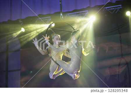 Circus actress acrobat performance. Two girls perform acrobatic elements in the air ring. Circus actress acrobat performance. Two girls perform acrobatic elements in the air ring. 128205348