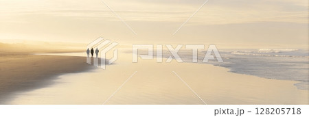 Three individuals walking along a serene beach at sunset, with gentle waves lapping at the shore and a soft golden glow illuminating the scene 128205718