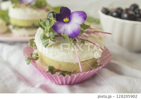 Vegetarian appetizer with cucumber slices, microgreens and feta cheese garnished with fresh purple flowers. 128205902