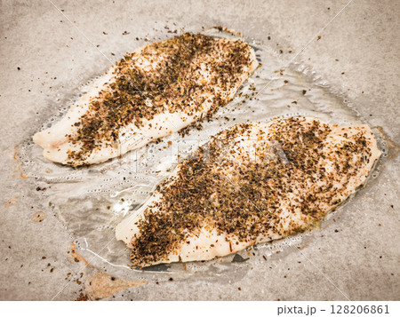 Fresh fish fillets cod seasoned with herbs and spices ready for cooking on a baking sheet showcasing culinary preparation healthy eating concept 128206861
