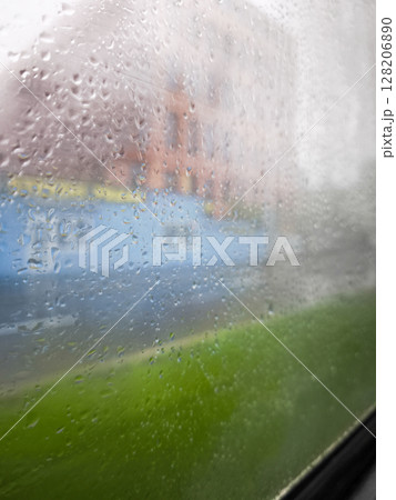 Rainy window view with droplets creating a blurred effect on the outside scenery showcasing urban life and nature elements in a serene atmosphere concept 128206890