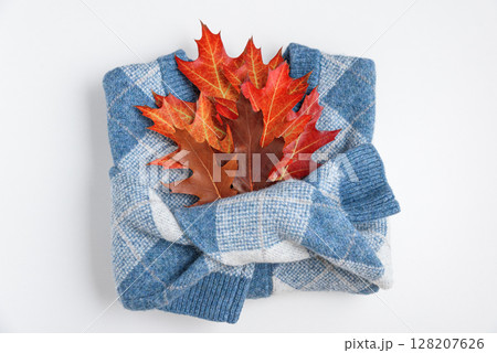 Autumn folded sweater with oak leaves on white background. Top view 128207626