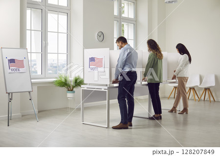 People standing back at vote center in voting booth with usa flags on election day. People standing back at vote center in voting booth with usa flags on election day. 128207849
