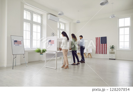 Election day, us polling office, voters stand, participate to mark ballot paper in booth Election day, us polling office, voters stand, participate to mark ballot paper in booth 128207854