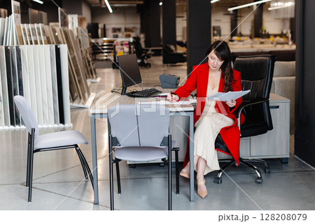 Businesswoman working at desk in tile store taking notes on documents Businesswoman working at desk in tile store taking notes on documents 128208079