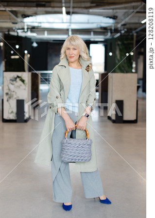 Stylish Woman in Modern Office Setting Holding Fashionable Handbag 128208119
