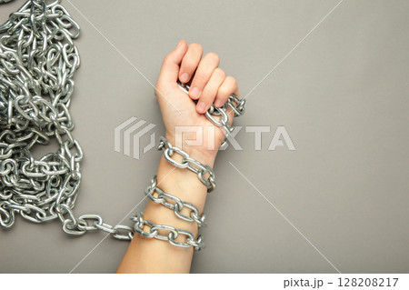 Hands are chained in chains on grey background. Space for text 128208217