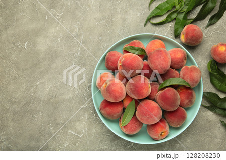 Sweet peaches and leaves on mint plate on grey concrete background. Space for text 128208230